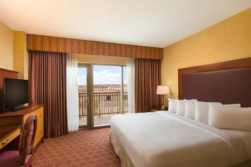 a hotel room with a large bed and a balcony at Embassy Suites by Hilton Charlotte Concord Golf Resort & Spa in Concord