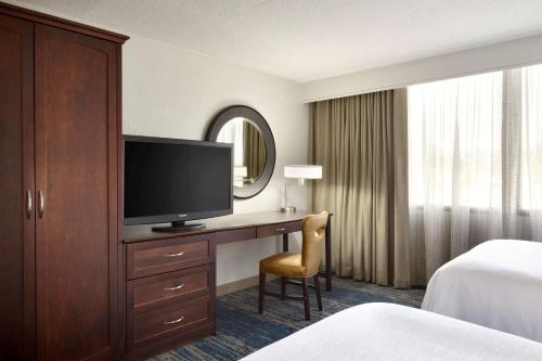 a hotel room with a desk with a flat screen tv at Embassy Suites by Hilton Columbus in Columbus