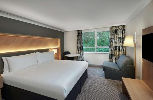 Habitación de hotel con cama y silla en Hilton Cobham, en Cobham