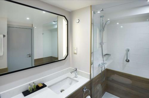 a bathroom with a shower and a sink and a mirror at Hilton Cobham in Cobham