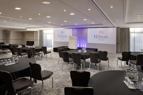 a conference room with tables and chairs and a screen at Hilton Cobham in Cobham