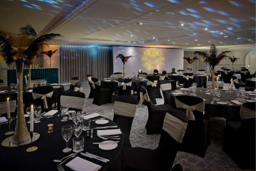a banquet hall with black tables and chairs at Hilton Cobham in Cobham