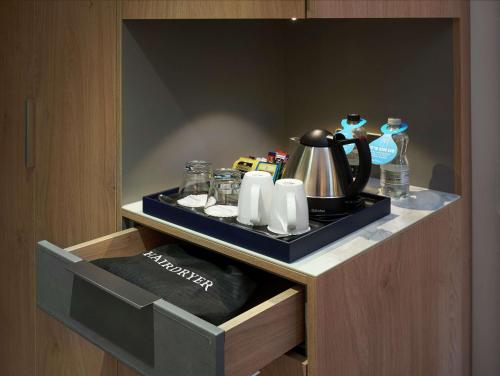 a tray with a tea kettle and cups on a counter at Hilton Cobham in Cobham