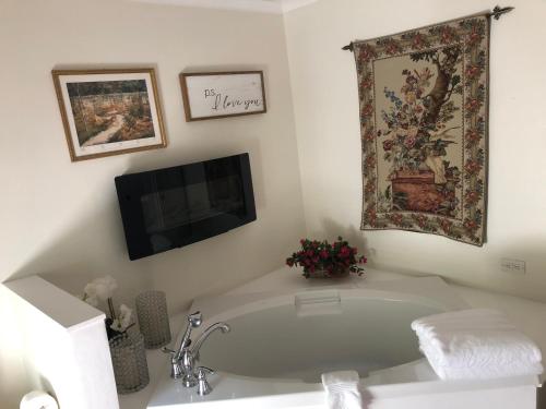 baño blanco con bañera y TV en 18 Vine Inn & Carriage House, en Hammondsport