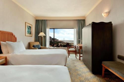 a hotel room with two beds and a desk and a window at Hilton Colombo Hotel in Colombo