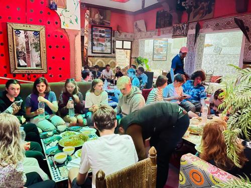 Eine Gruppe von Menschen, die an Tischen sitzen und Essen essen. in der Unterkunft Hostel Marrakech Rouge in Marrakesch