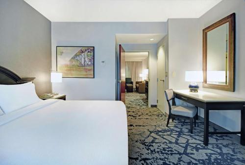 a hotel room with a bed and a desk and a bedroom at Embassy Suites Charleston in Charleston