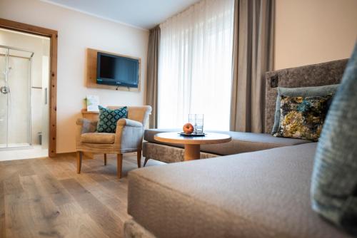 a hotel room with a couch and a table at Vitalpina Hotel Waldhof in Rablà