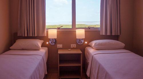 Duas camas num pequeno quarto com uma janela em Salinas Park Resort em Salinópolis