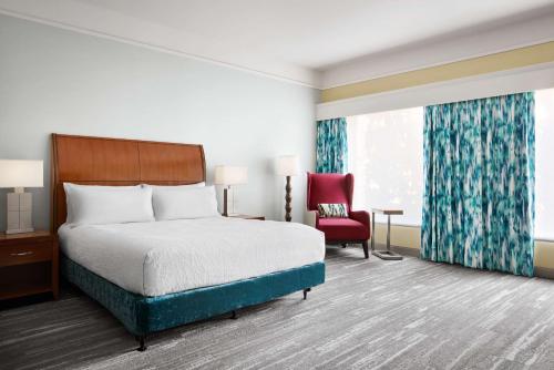 a hotel room with a bed and a red chair at Hilton Garden Inn Dallas Richardson in Richardson