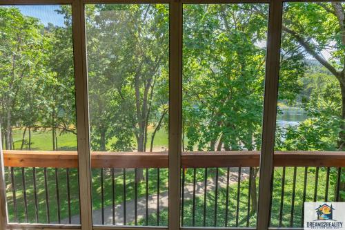 a screened in porch with a view of a park at 3BR Condo with Lake View - Trout Fishing - Playground - 2 Pools - Stairs Required - FREE TICKETS INCLUDED - PR69-9 in Branson