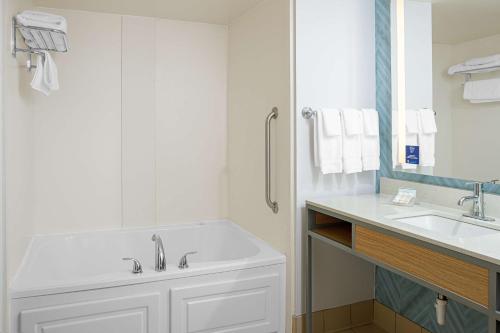 Baño blanco con lavabo y espejo en Hilton Garden Inn Fredericksburg en Fredericksburg