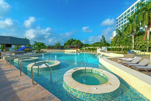 a large swimming pool with chairs and a building at Hilton Cartagena in Cartagena de Indias