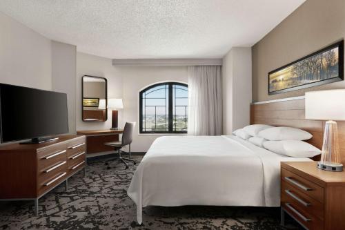 a hotel room with a bed and a flat screen tv at Embassy Suites Dallas - DFW Airport North in Grapevine