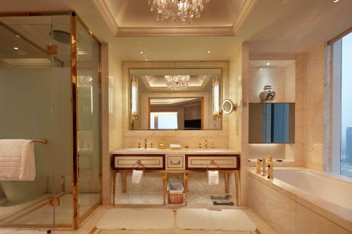 La salle de bains est pourvue d'une baignoire, d'un lavabo et d'un miroir. dans l'établissement Conrad Dalian, à Dalian