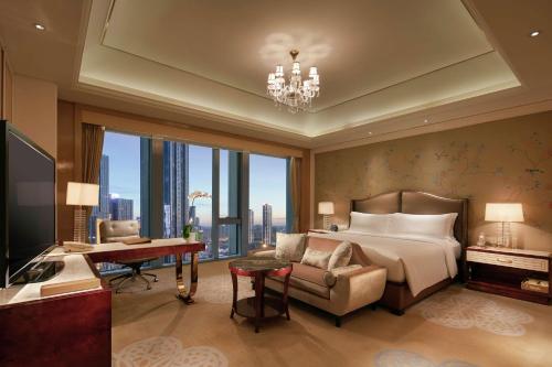 a bedroom with a bed and a couch and a desk at Conrad Dalian in Dalian
