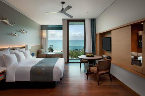 Rayong Marriott Resort & Spa في كلانج: غرفة نوم بسرير وطاولة وتلفزيون