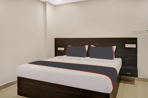 Schlafzimmer mit einem großen Bett mit einem Kopfteil aus Holz in der Unterkunft Super Collection O Hotel Pnr International Mehdipatnam in Hyderabad