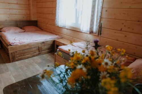 a bedroom with two beds and a window and flowers at Drevenice Horné Kysucé in Vysoká nad Kysucou