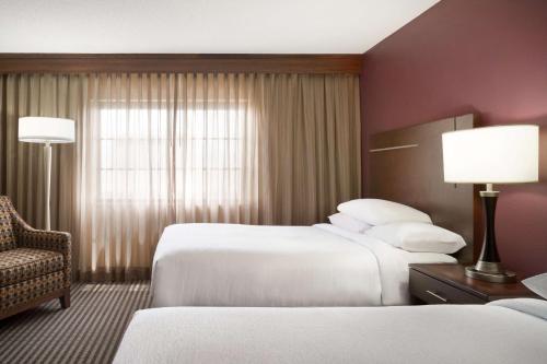 a hotel room with two beds and a chair at Embassy Suites Des Moines Downtown in Des Moines