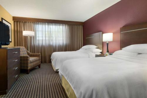 um quarto de hotel com duas camas e uma cadeira em Embassy Suites Des Moines Downtown em Des Moines