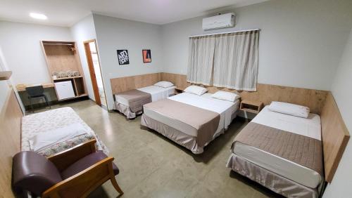 a hospital room with three beds and a couch at Hotel Pousada Parque das Águas in Olímpia