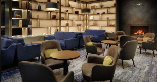a waiting room with blue chairs and tables and a fireplace at Hilton Dublin Airport in Cloghran