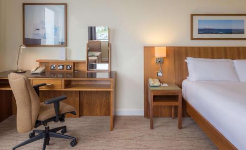a hotel room with a bed and a desk and a bedroom at Hilton Dublin Airport in Cloghran