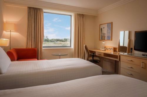 a hotel room with two beds and a desk and a window at Hilton Dublin Airport in Cloghran