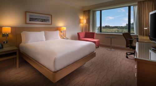 a hotel room with a bed and a desk and a window at Hilton Dublin Airport in Cloghran