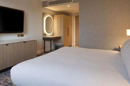 a bedroom with a large white bed and a television at Hilton Dublin Airport in Cloghran