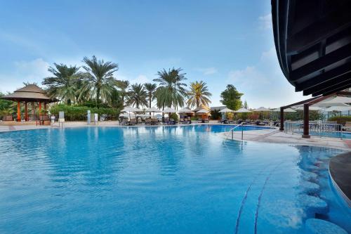 a large blue swimming pool with palm trees and umbrellas at Hilton Dubai The Walk in Dubai