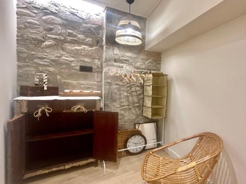 een kamer met een stenen muur met een klok en een stoel bij Apartamento colgante al río con vistas al puente in Camprodon