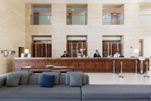 a lobby with a bar in a building with people at Hilton Vilamoura in Vilamoura