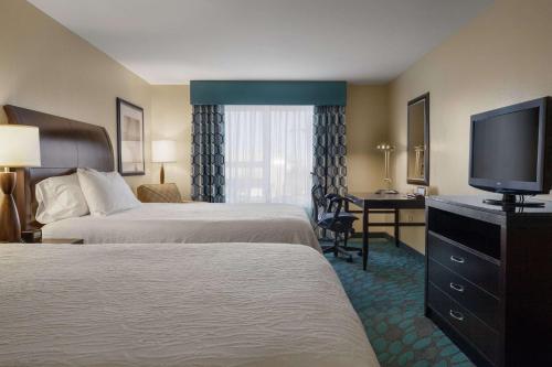 a hotel room with two beds and a flat screen tv at Hilton Garden Inn Fargo in Fargo