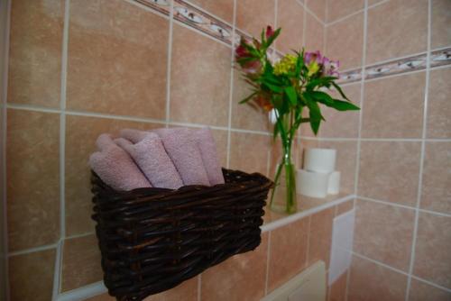 a bathroom with a basket of towels and a vase of flowers at Apartmány Braníčkov in Branickov