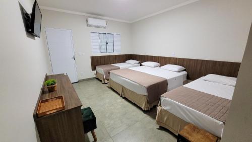a hotel room with two beds and a television at Hotel Pousada Parque das Águas in Olímpia