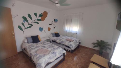 um quarto com duas camas e uma planta na parede em Casa en zona rural a 200 m de Ariño (Teruel) em Ariño