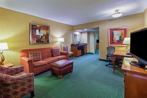 a hotel room with a couch and a desk at Embassy Suites by Hilton Greensboro Airport in Greensboro