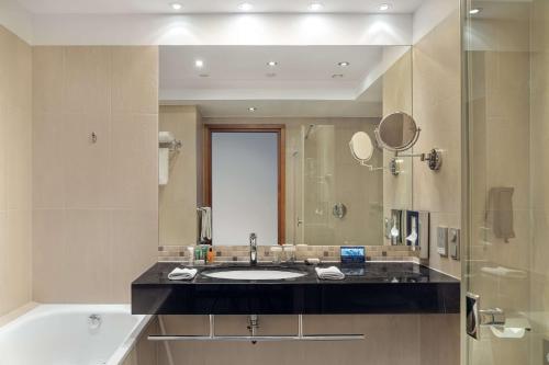 a bathroom with a sink and a tub and a mirror at Hilton Gdansk in Gdańsk