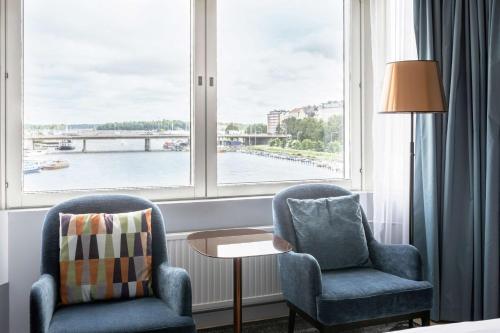 two chairs and a table in a room with a window at Hilton Helsinki Strand in Helsinki