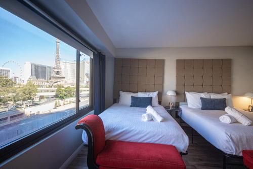 a bedroom with two beds and a window with the eiffel tower at Stay Together Suites on The Strip - 1 Bedroom Apartment with View 656 in Las Vegas