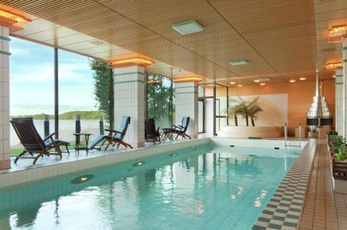 uma piscina com cadeiras e mesas num edifício em Hilton Helsinki Kalastajatorppa em Helsinque