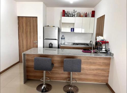 una cocina con barra y 2 taburetes en Departamento de Lujo en con Alberca Panoramica en Zona Metropolitana de Guadalajara en Guadalajara