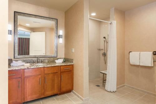 a bathroom with a sink and a shower with a mirror at Hilton Promenade Branson Landing in Branson