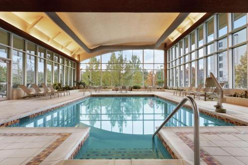 a swimming pool in a building with windows at Embassy Suites Huntsville in Huntsville
