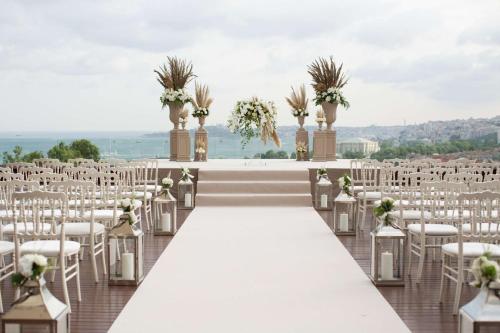 eine Hochzeitszeremonie mit weißen Stühlen und einem langen Gang in der Unterkunft Conrad Istanbul Bosphorus in Istanbul