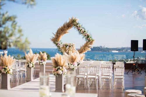 einen Tisch mit Stühlen und einen Hochzeitsbogen mit Blumen in der Unterkunft Conrad Istanbul Bosphorus in Istanbul