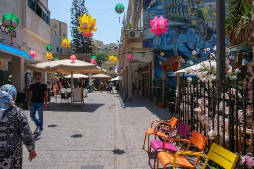 Appartement cosy sur Netanya في نتانيا: امرأة تمشي في الشارع مع الكراسي والطاولات