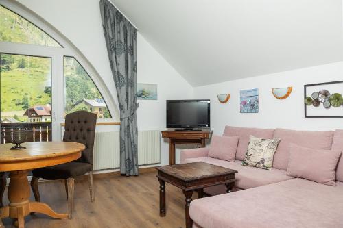 Una sala de estar con un sofá, una mesa y un televisor. en Appartements Alpengarten, en Mallnitz